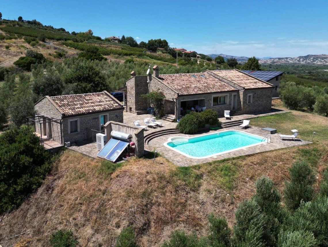 Il casale in pietra con la piscina e la valle sullo sfondo