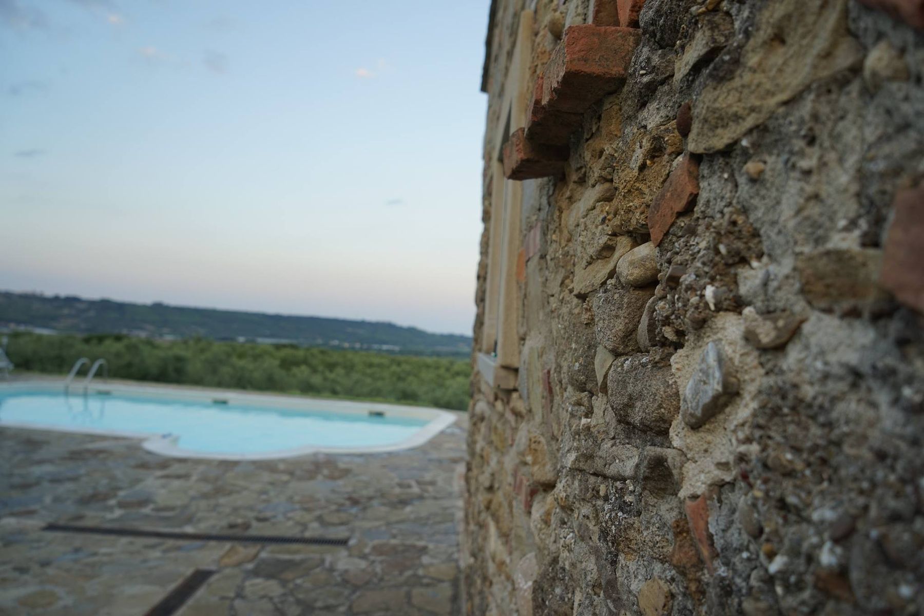 Muro in pietra e piscina al tramonto